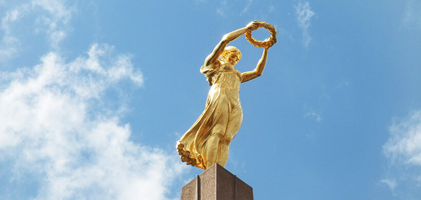 A golden statue of a women holding a wreath